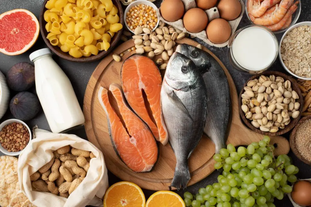 Overhead view of nutrient-rich foods including salmon, fish, eggs, nuts, fruits, grains, and dairy