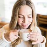young woman smiling while drinking a cup of coffee