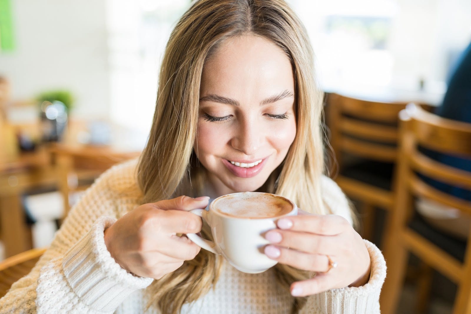 young woman smiling while drinking a cup of coffee