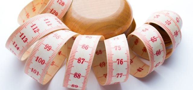 Yo-yo effect in diet concept. Wooden yoyo with centimeter measure. Isolated on white background.