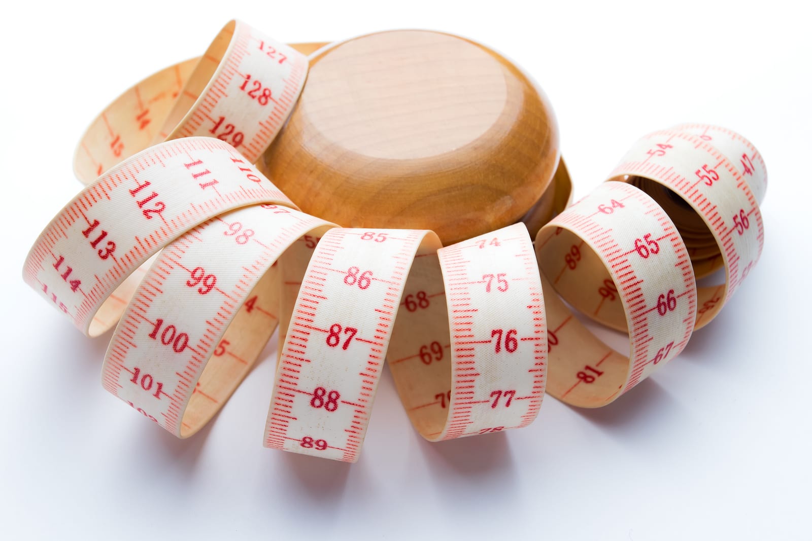 Yo-yo effect in diet concept. Wooden yoyo with centimeter measure. Isolated on white background.