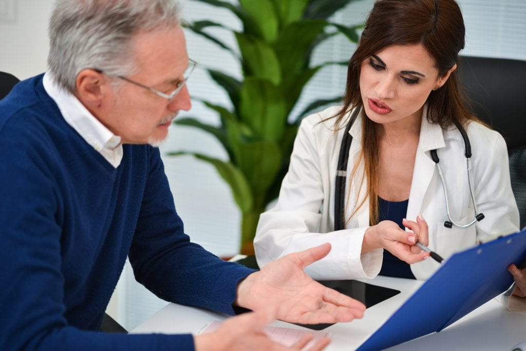 Doctor talking to his patient and showing documents. Focus on the doctor