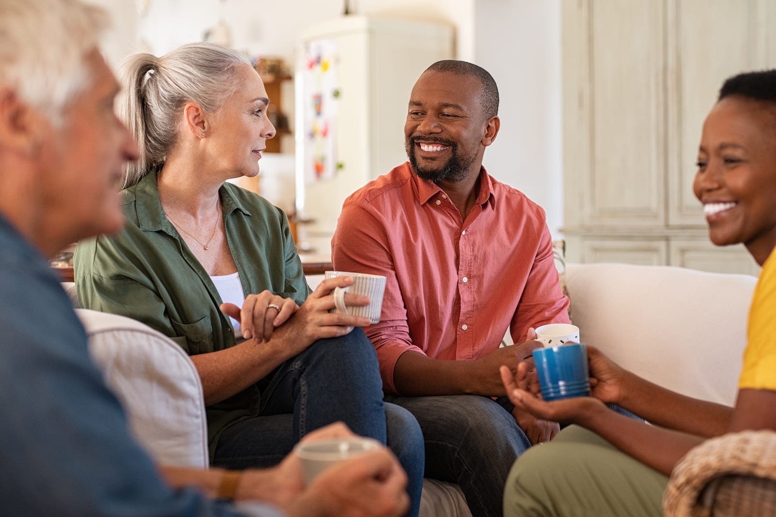 A group of happy older adults sit drinking coffee in a social get-together.