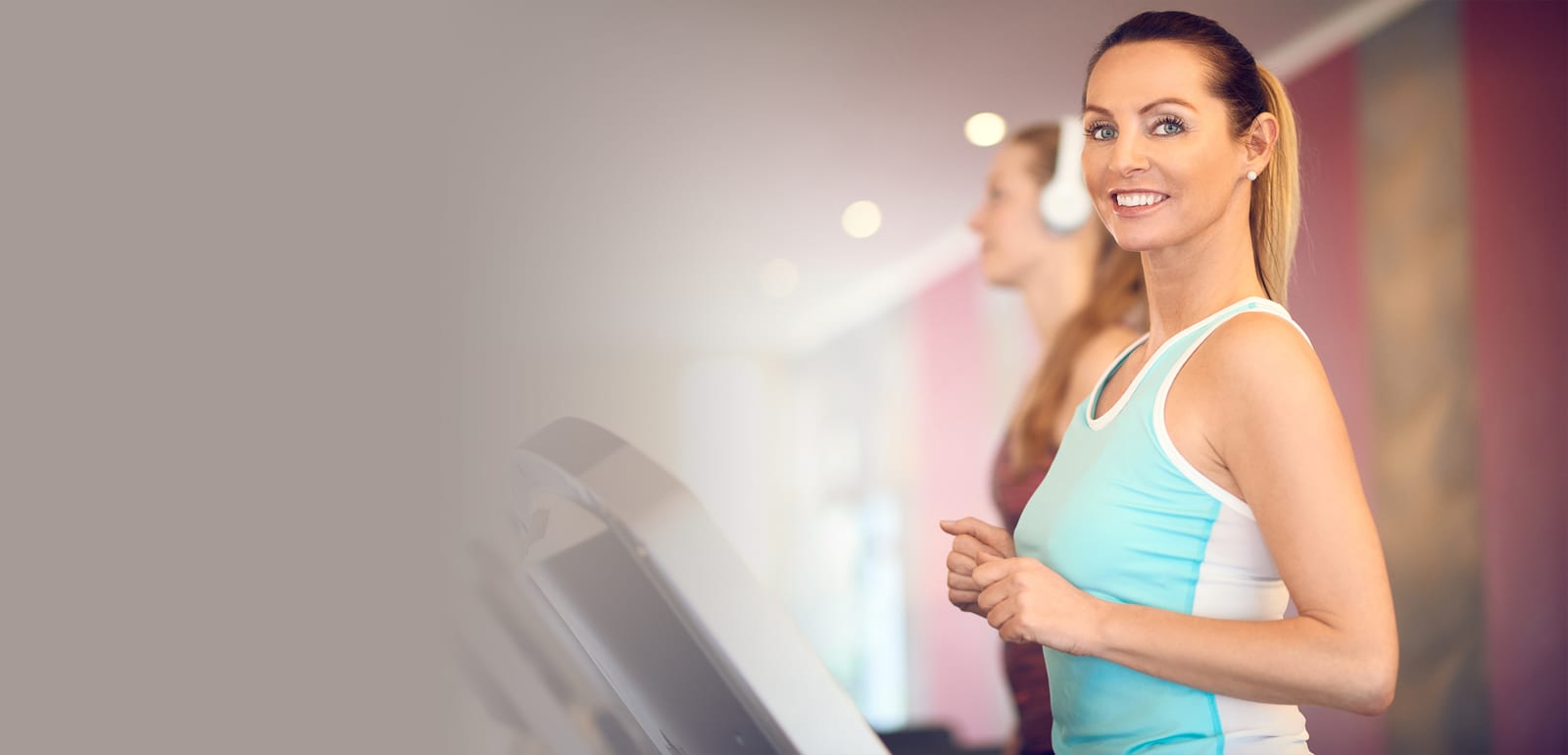 woman working out on a treadmill smiling at the camera