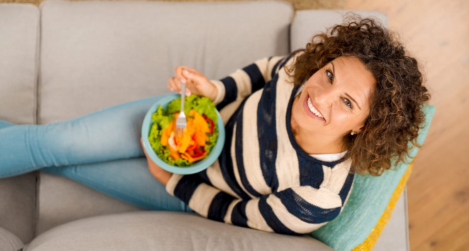 Top view of a beautiful woman on the sofa eating a healthy salade