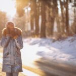 A woman taking a winter walk in the park, getting exercise and soaking up sunlight to help boost her energy during the colder months.