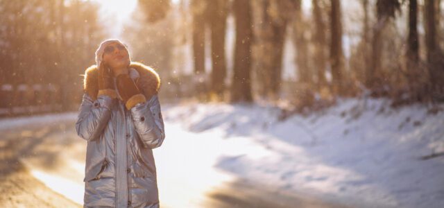 A woman taking a winter walk in the park, getting exercise and soaking up sunlight to help boost her energy during the colder months.