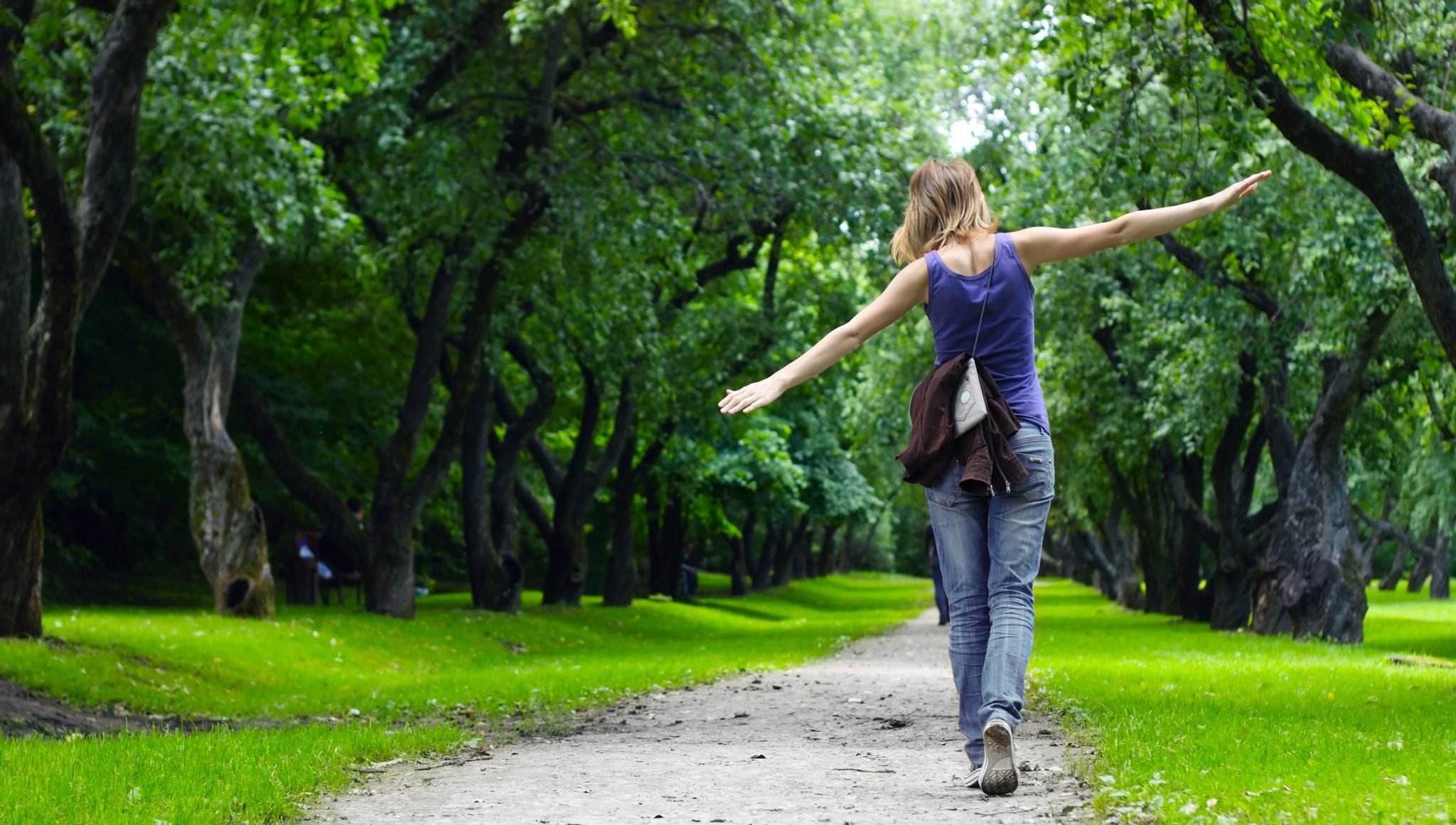 Woman walking on path in green summer park